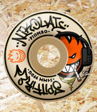 A single skateboard wheel shown from above on a wood shavings background. The wheel is cream-colored with black and orange graphics, including the text 'Nikolai Piombo' and a cartoon character wearing headphones and smoking.